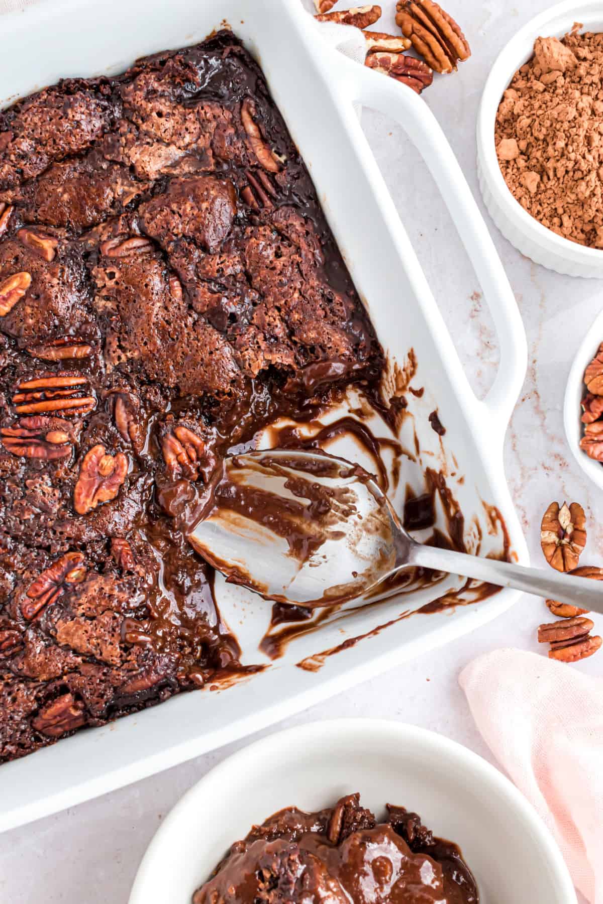 Chocolate cobbler with pecans in a white baking dish.