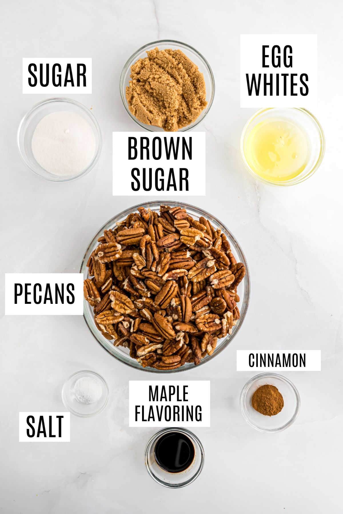 Bowls with labeled ingredients for Maple Brown Sugar Pecans: pecans, sugar, brown sugar, egg whites, cinnamon, salt, and maple flavoring.