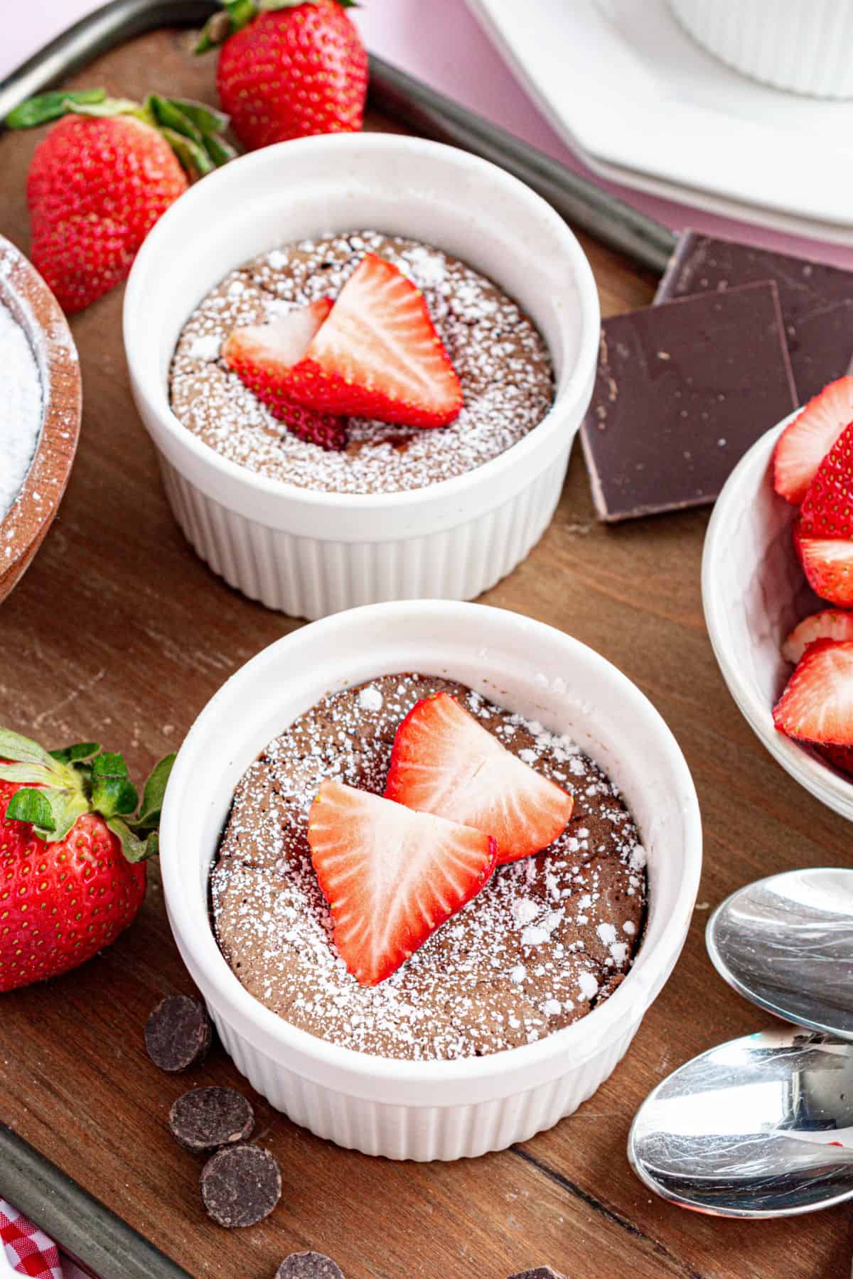 Chocolate molten cakes in ramekins with strawberry garnish.