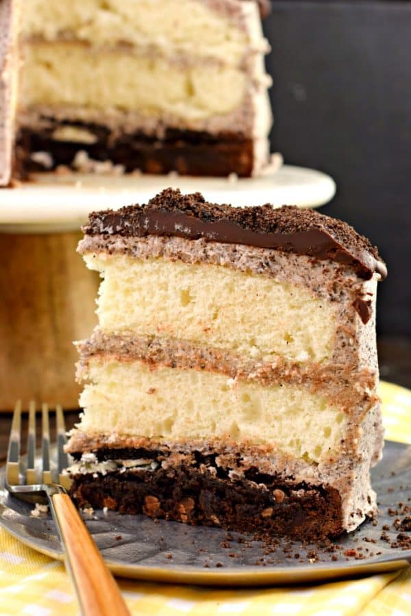 Oreo brownie bottom cake with two layers of white cake topped with ganache and frosting.