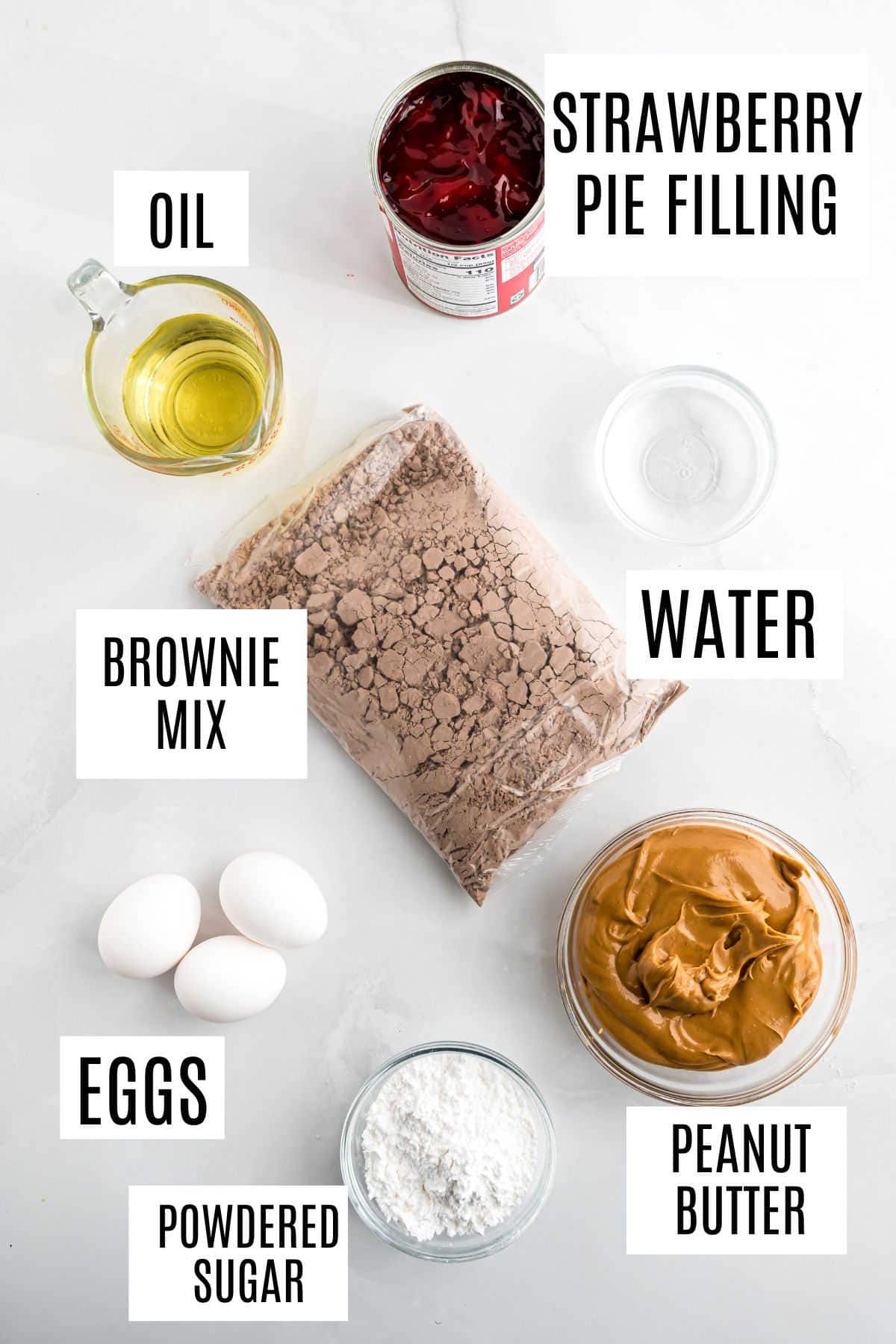 Brownie mix, peanut butter, eggs, oil, water, powdered sugar, and strawberry pie filling come together on a white surface to create delicious peanut butter jelly brownies.