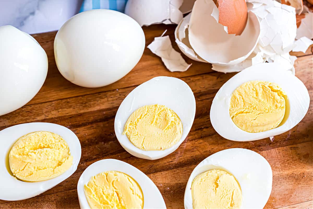 Hard boiled eggs peeled on a wooden cutting board, and cut in half.