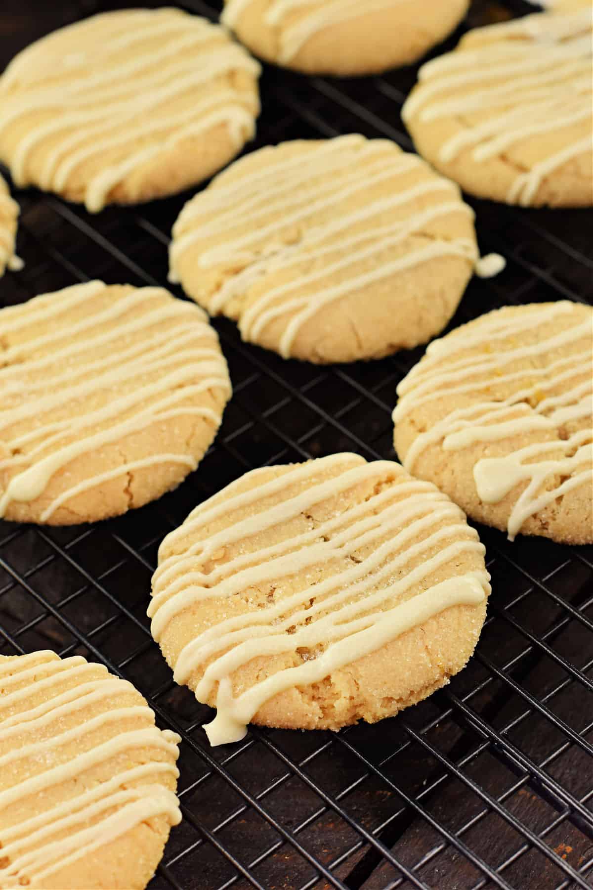 Lemon cookies with white chocolate drizzled on top on a wire cooling rack.