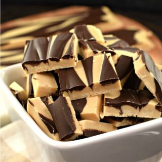 Chocolate peanut butter fudge swirled and cut into pieces in a white bowl.