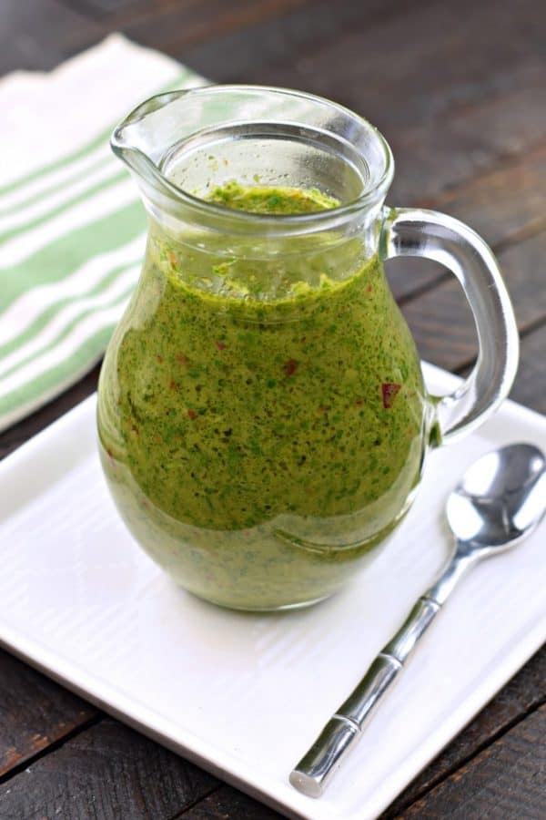 Fresh green chimichurri sauce in clear glass pitcher with spoon, vibrant, chimichurri, tex mex