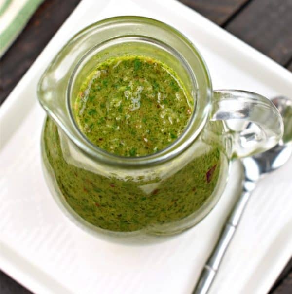 Fresh green chimichurri sauce in clear glass pitcher with spoon, vibrant, chimichurri, tex mex