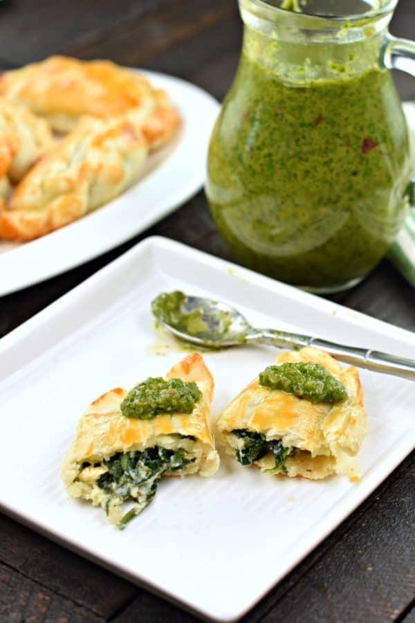 Fresh green chimichurri sauce spooned on top of spinach and cheese empanadas