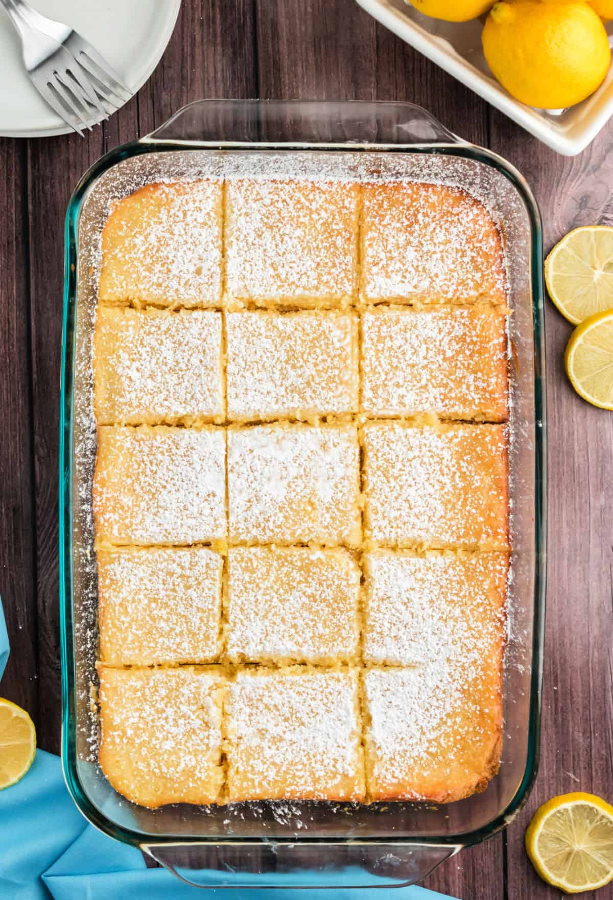 Gooey lemon cake bars in a 13x9 glass dish cut into squares.