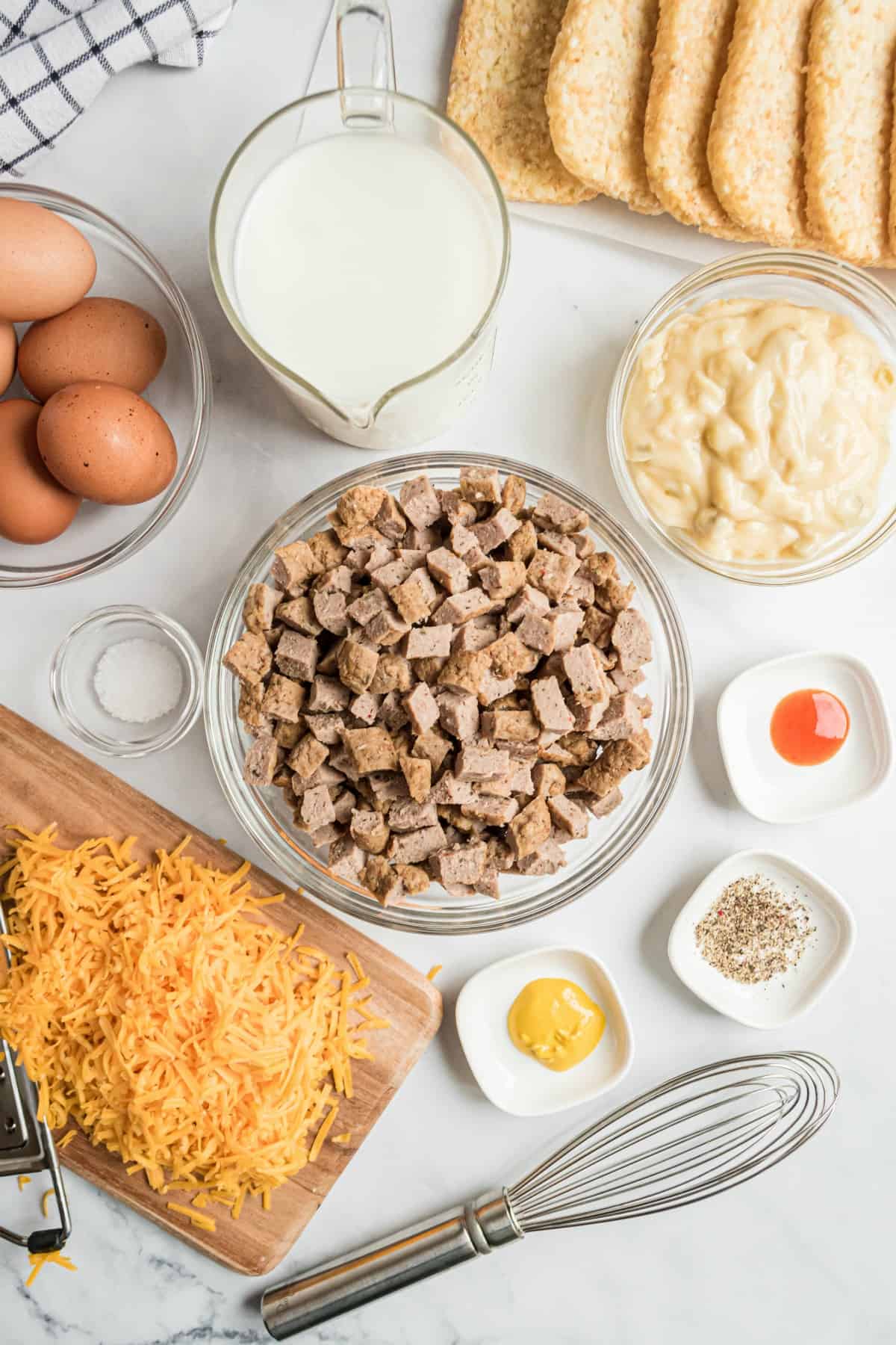 Ingredients needed for egg casserole, including sausage, cheese, eggs, milk, and seasoning.