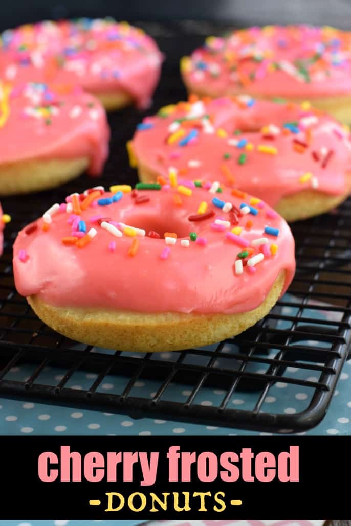 Baked donuts with cherry frosting and sprinkles on a wire cooling rack.