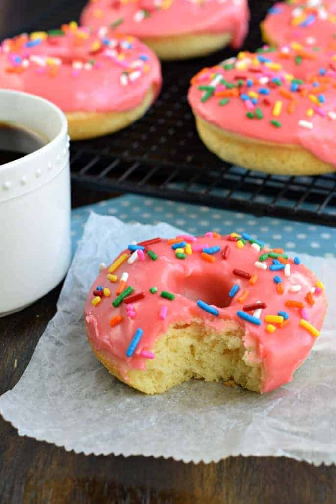 These Cherry Frosted Donuts have a tender, moist cake-like texture with a dreamy cherry frosting! Perfect for holidays, Valentine's Day, or general breakfast enjoyment. Cherry donut with a bite removed.