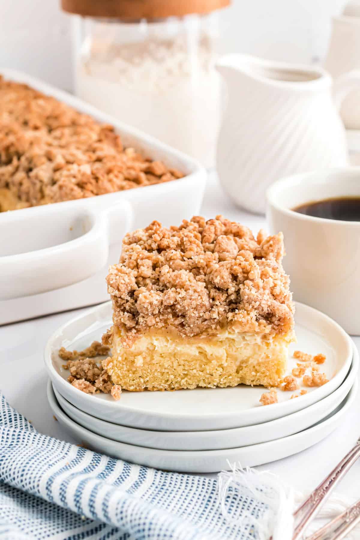 Slice of coffee cake topped with streusel on a stack of white plates.