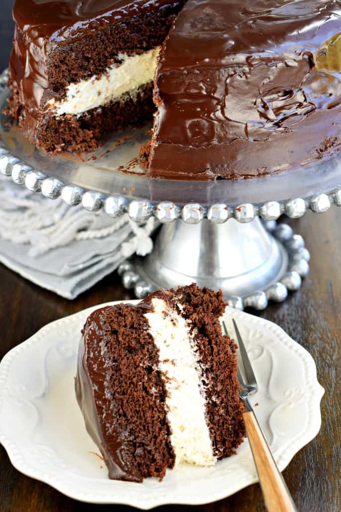 Slice of ding dong cake on white plate with cake platter in background.