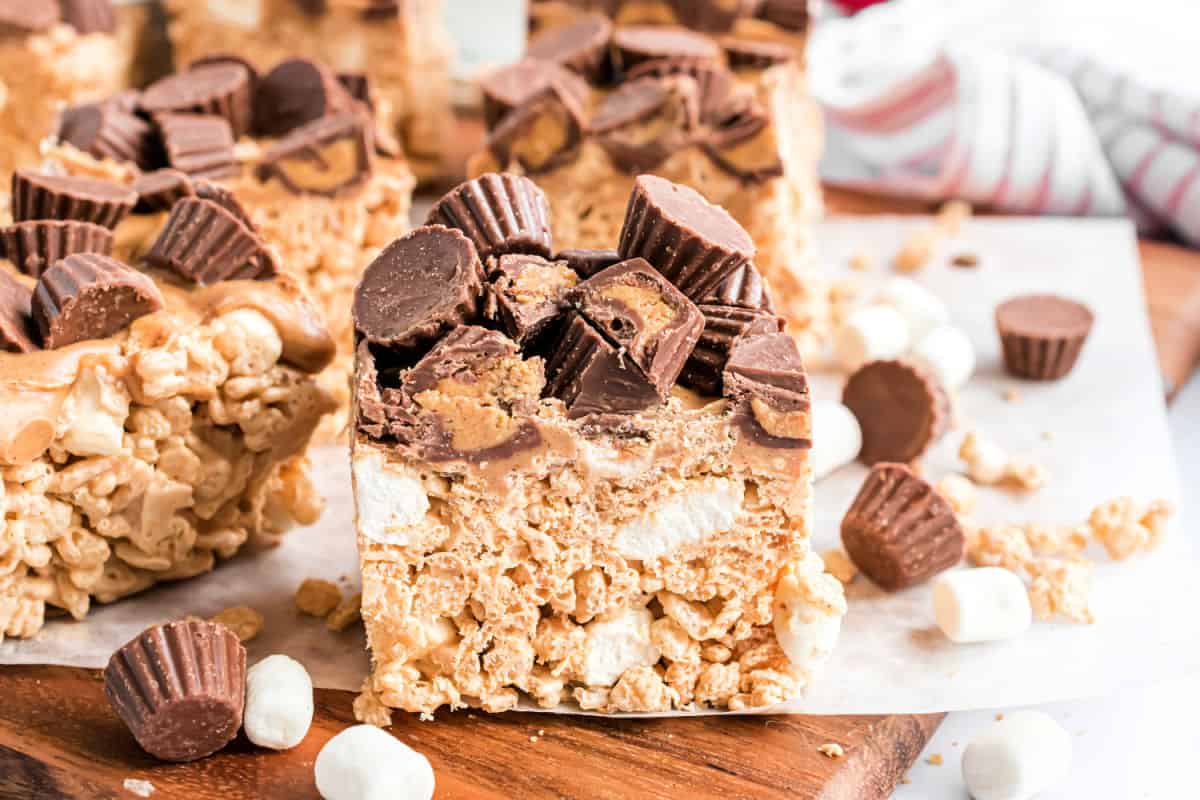 Peanut butter krispie treats on a wooden cutting board.