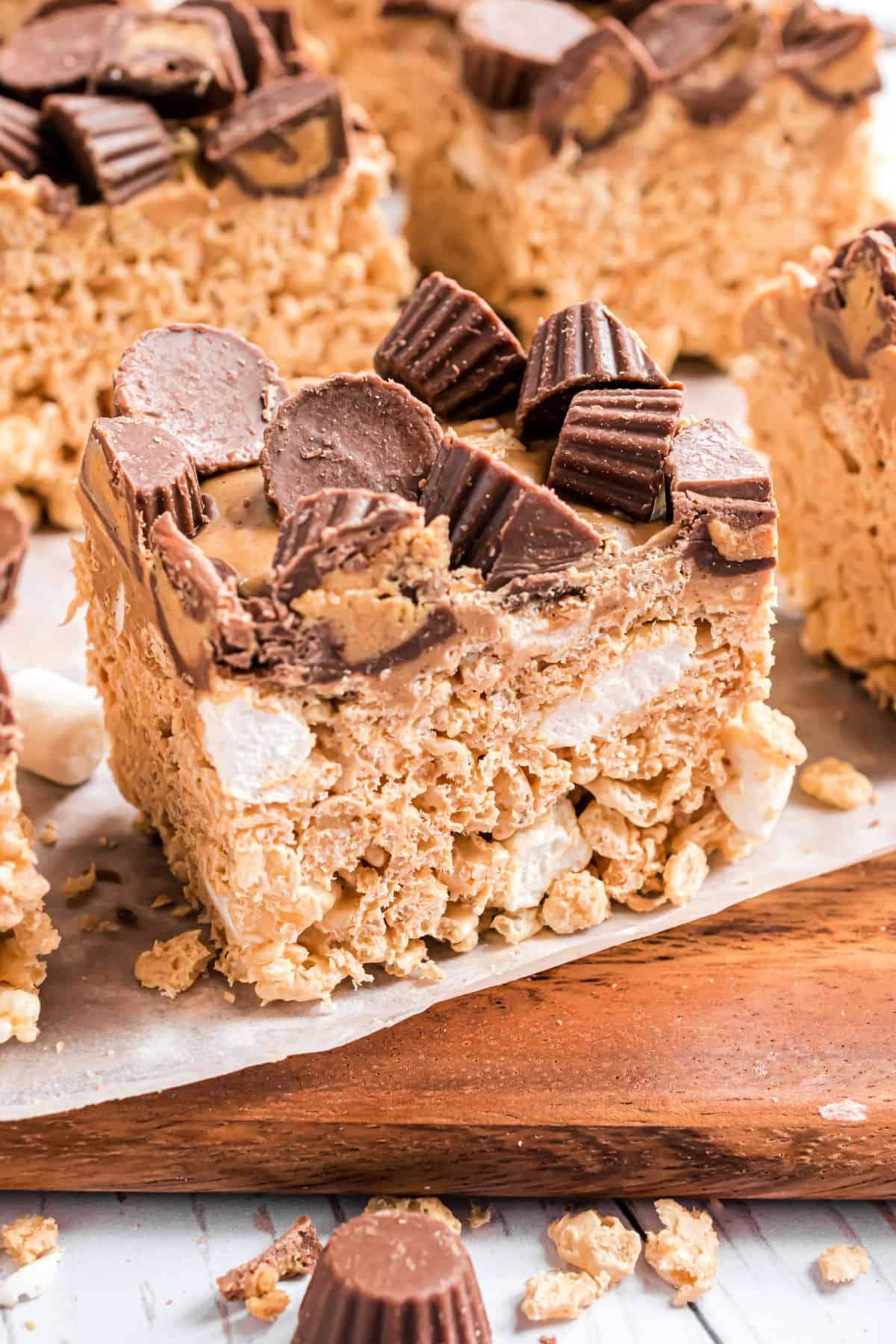 Large cut squares of peanut butter krispie treats with peanut butter cups on top.