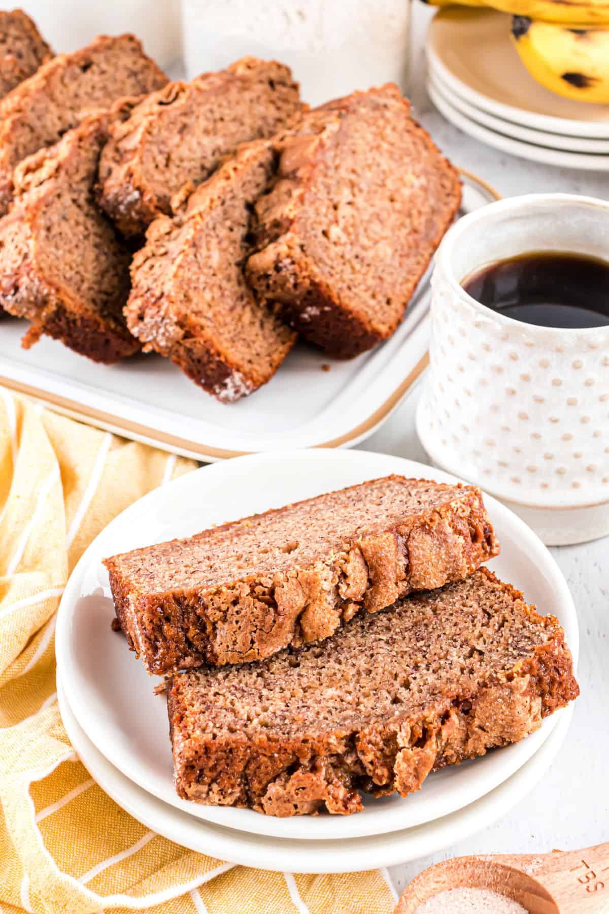 Two slices banana bread on a stack of white plates.