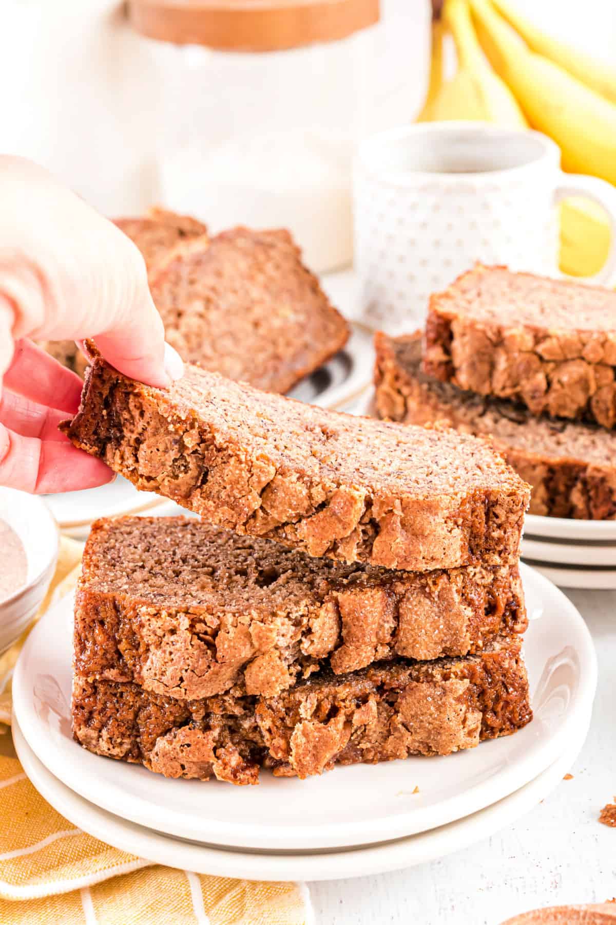 Three slices of snickerdoodle bread stacked on a white plate with the top slice being removed.