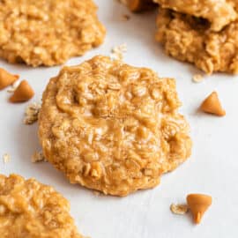 No bake oatmeal butterscotch cookies stacked on white parchment paper.