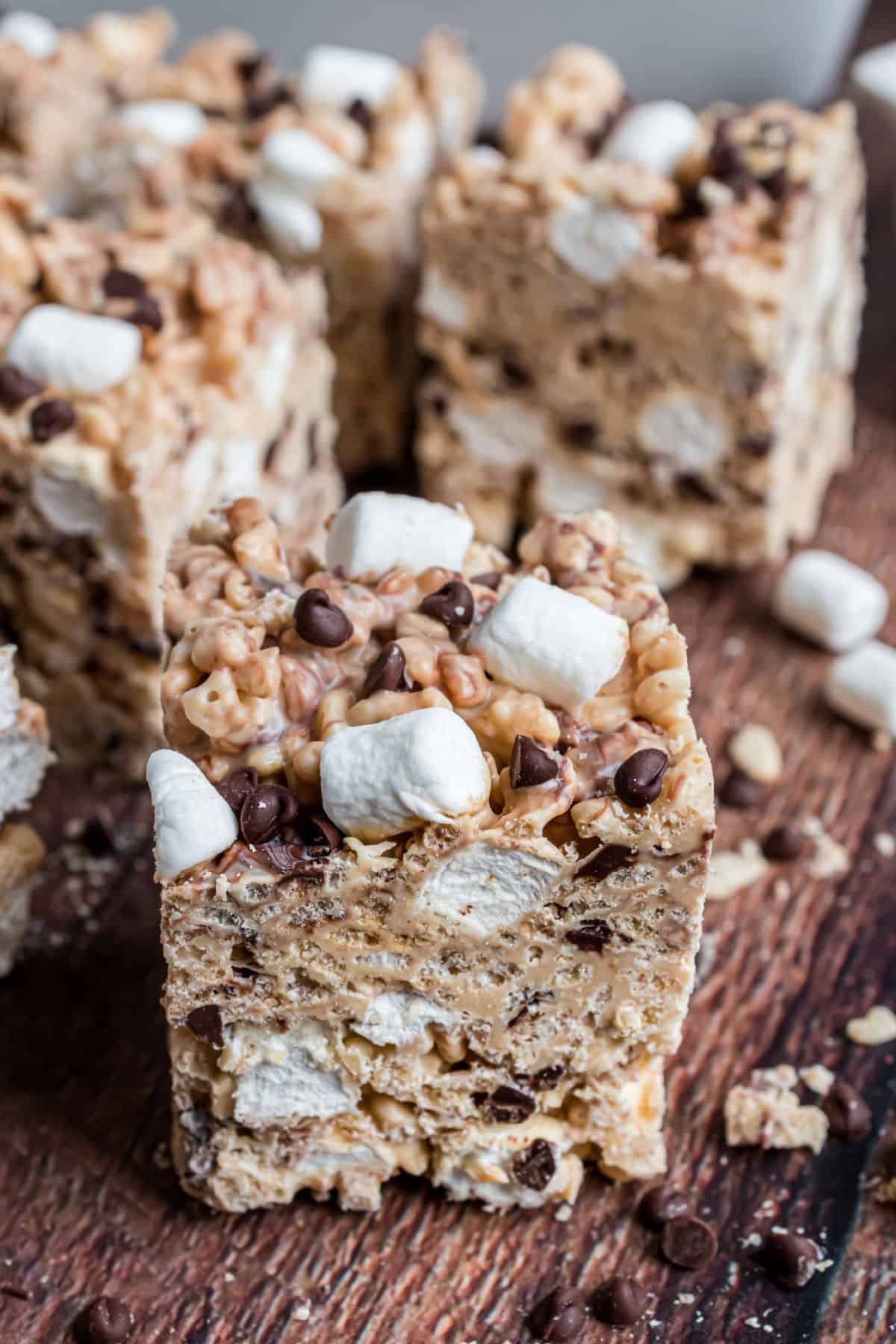 Thick square of avalanche rice krispie treats on wooden platter.