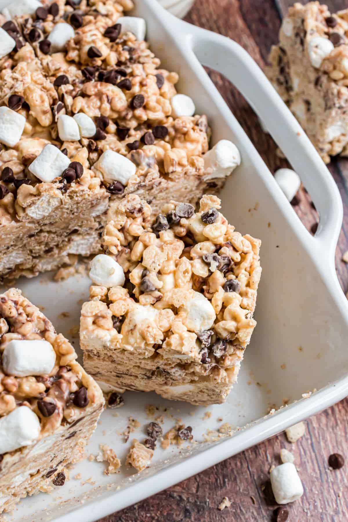 Peanut butter krispie treats with marshmallow and chocolate chips in a white baking dish.