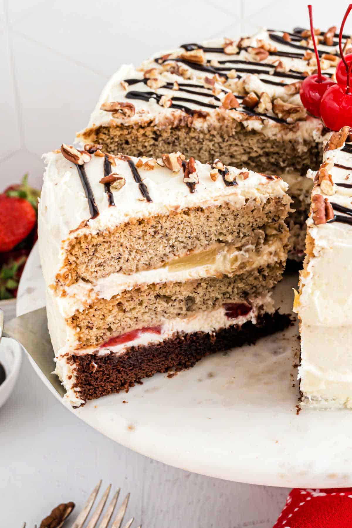 Slice of banana split cake being removed from cake stand.