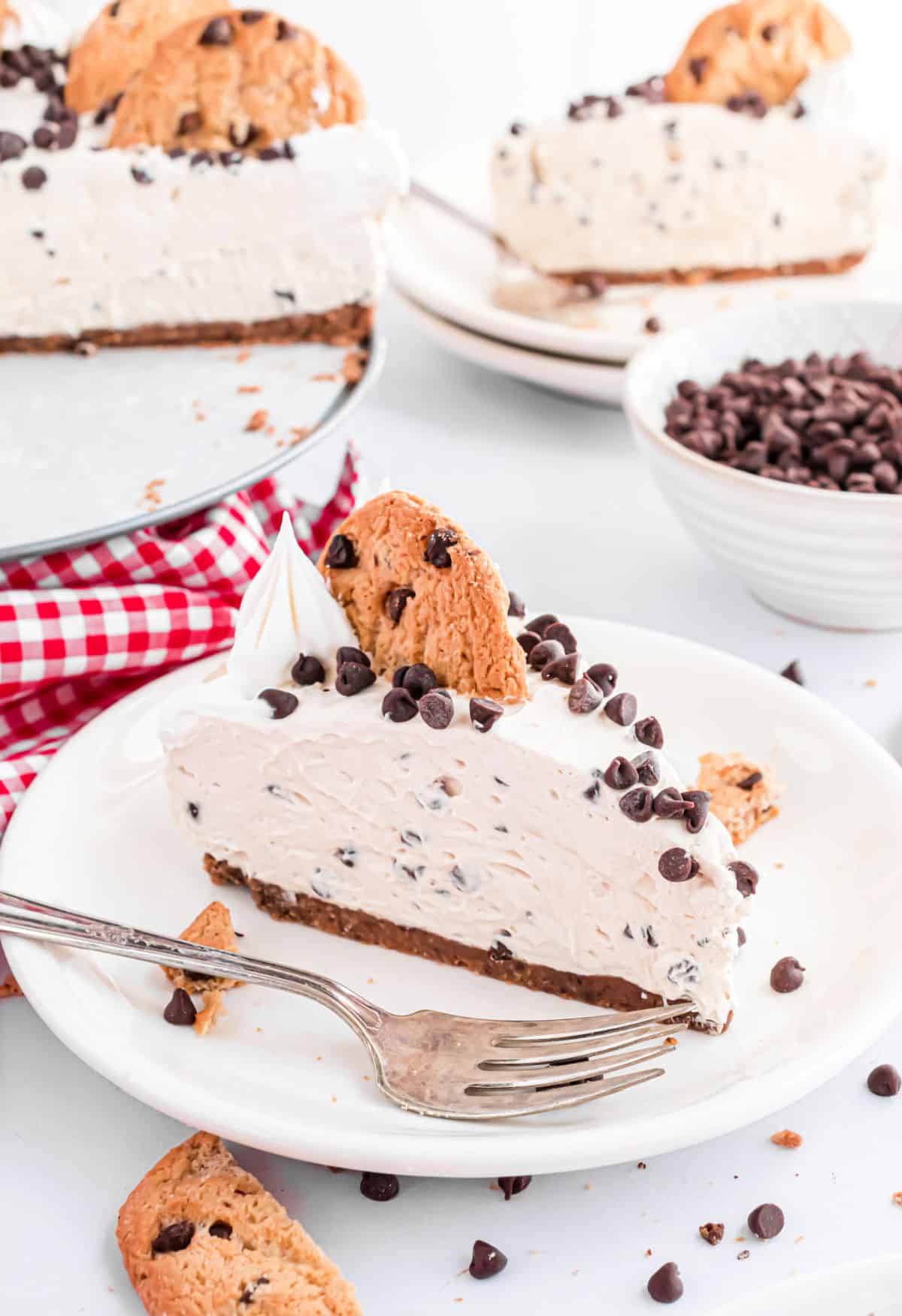 Slices of cheesecake with chocolate chip cookies and whipped cream.