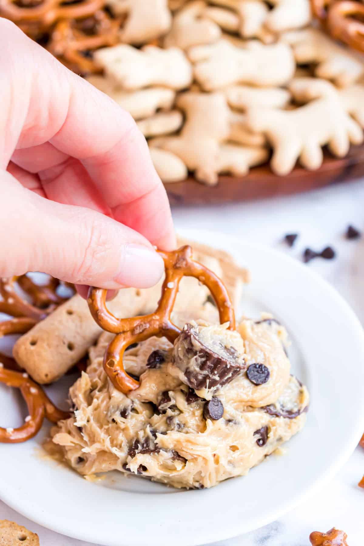 Pretzel being scooped into cookie dough dip with Reese's.