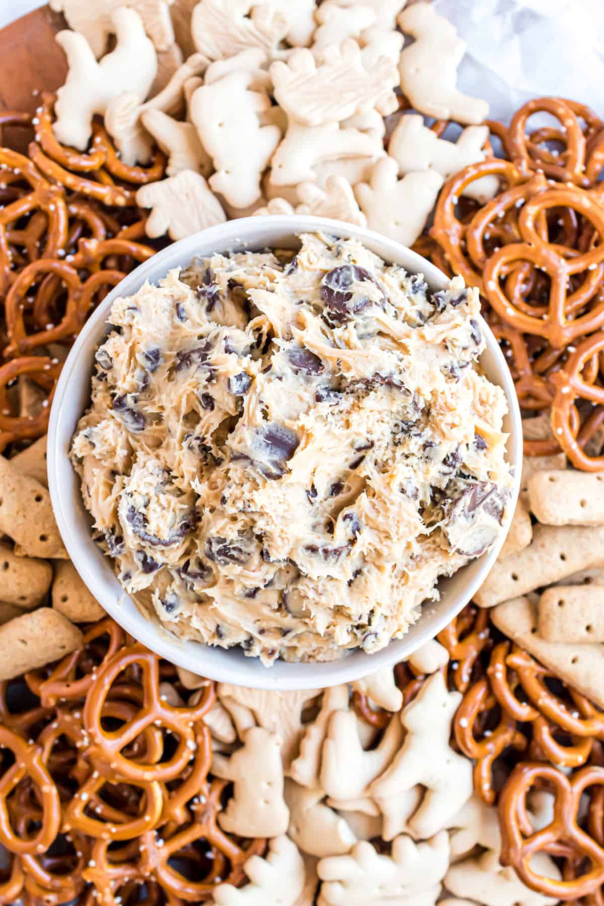 Peanut butter cookie dough dip in a bowl served with pretzels and animal crackers.