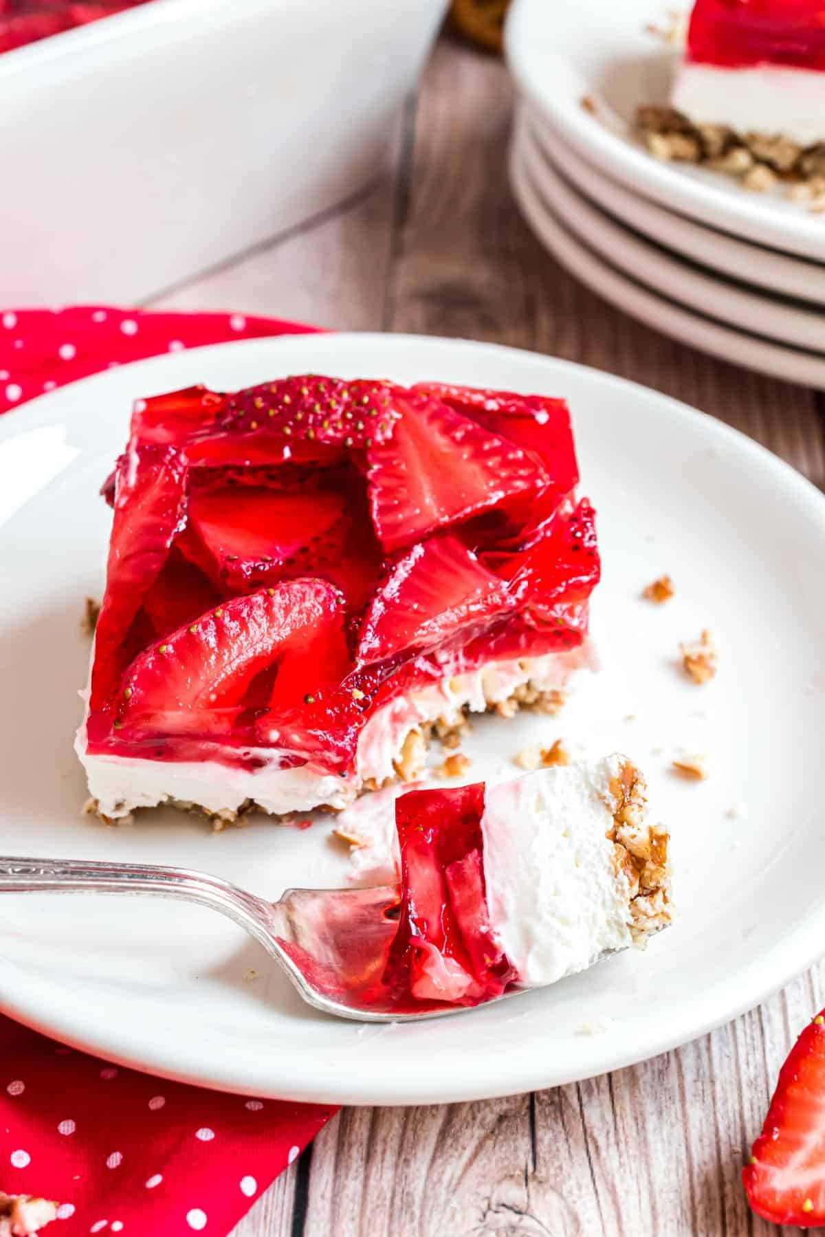 Slice of strawberry pretzel salad with a fork taking a bite.