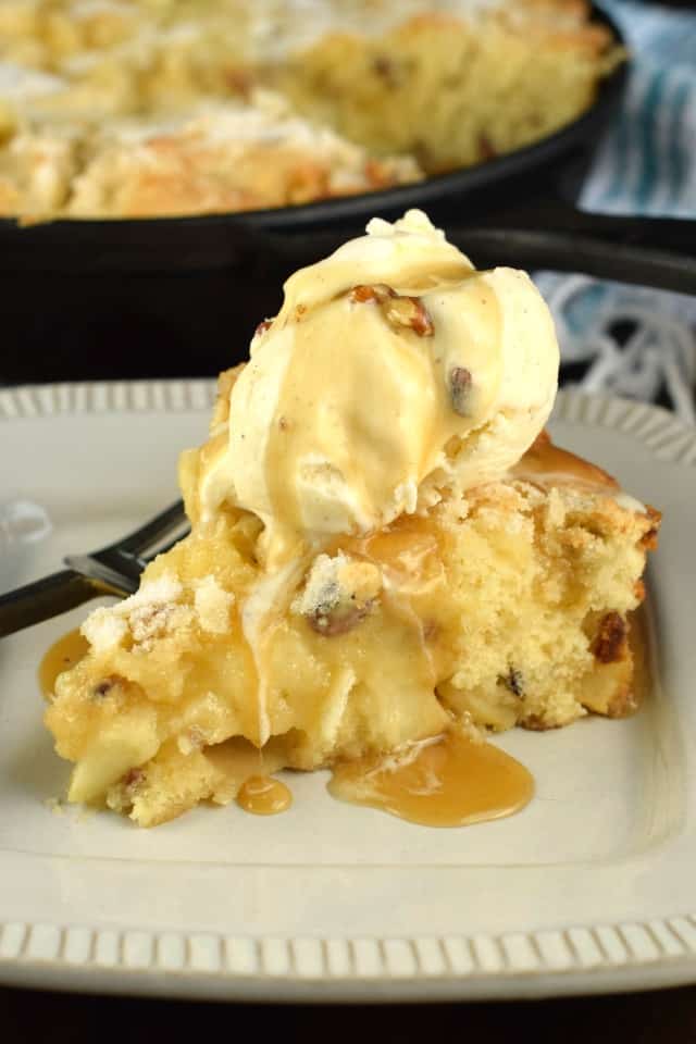 Slice of apple skillet cake topped with ice cream and bourbon caramel sauce.
