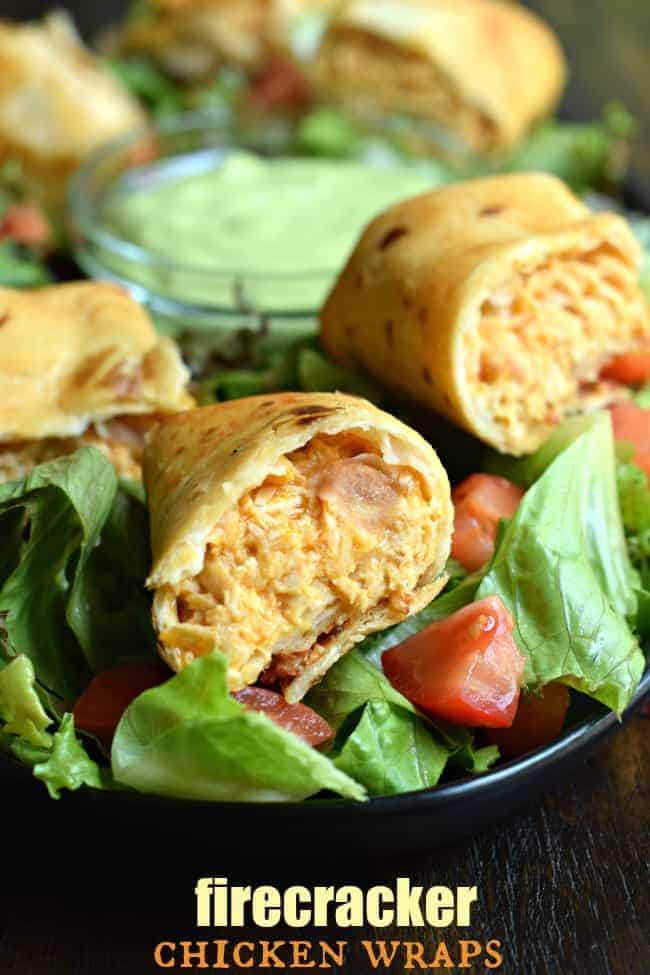 Firecracker chiken wraps on a bed of lettuce and tomatoes.