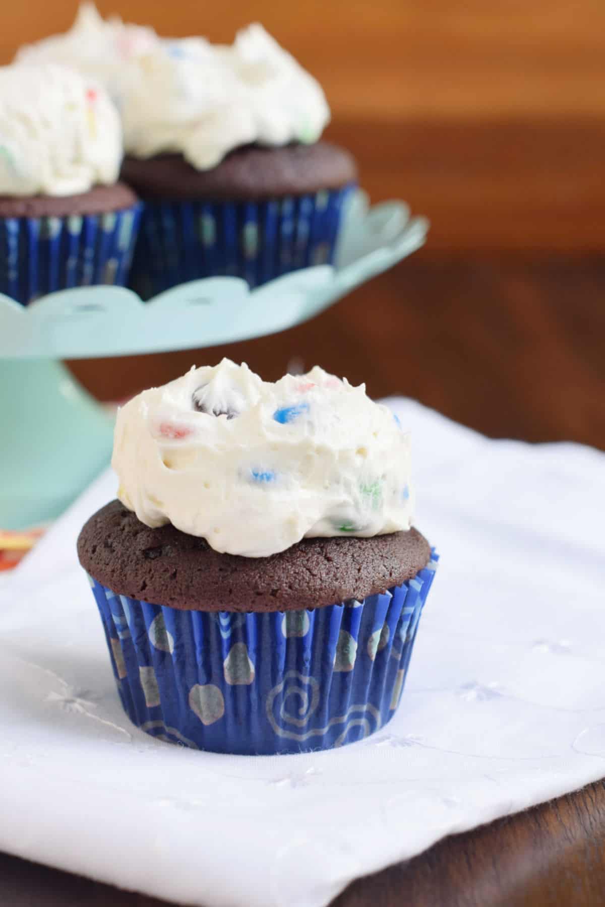 M&M frosted chocolate cupcake on a white linen.