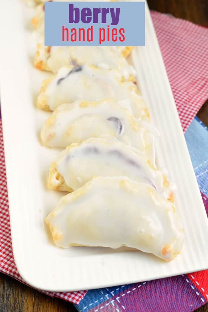 Berry hand pies with icing on a white platter.