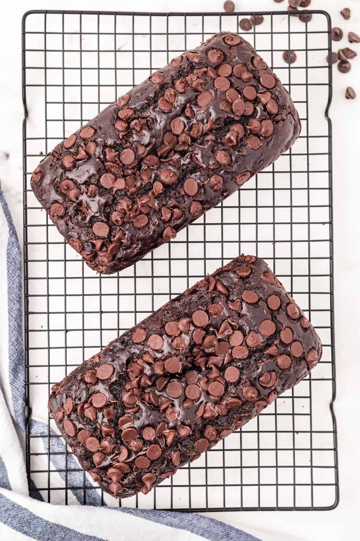 Two loaves of chocolate zucchini bread on wire cooling rack.