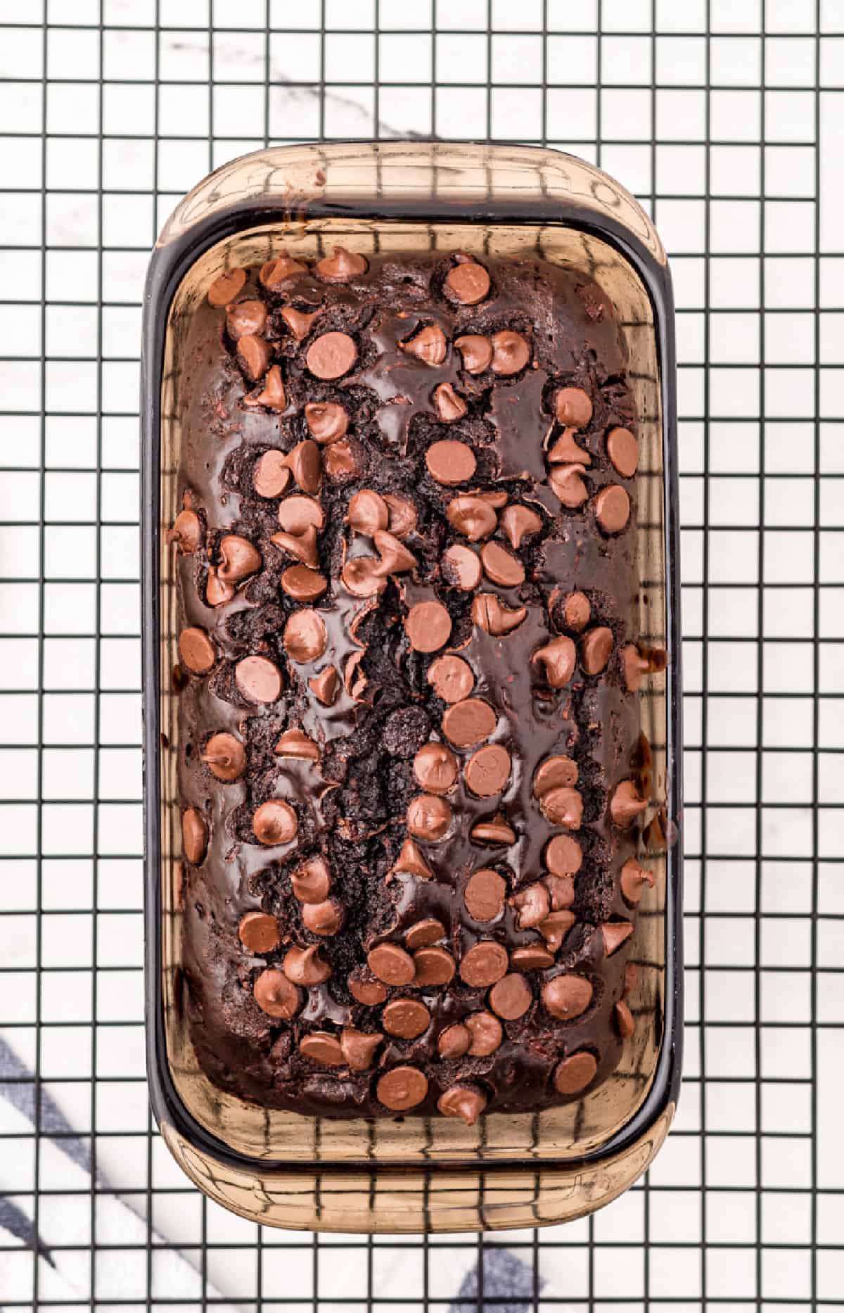 Loaf of chocolate zucchini bread in pan on wire rack.