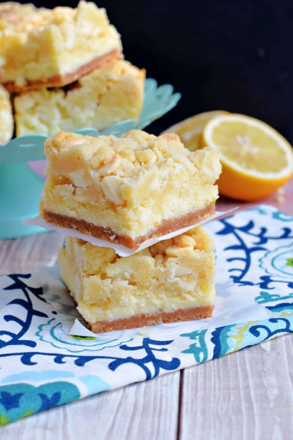 Two lemon cheesecake cookie bars stacked on top of eachother.