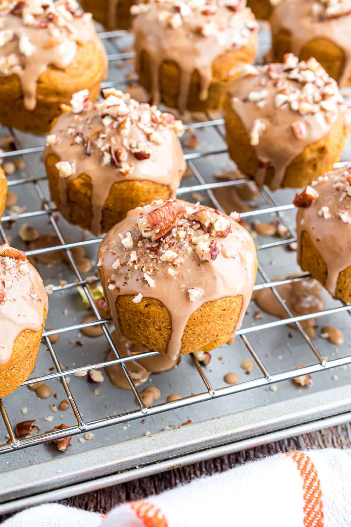 Mini muffins with glaze and pecans on a wire cooling rack.
