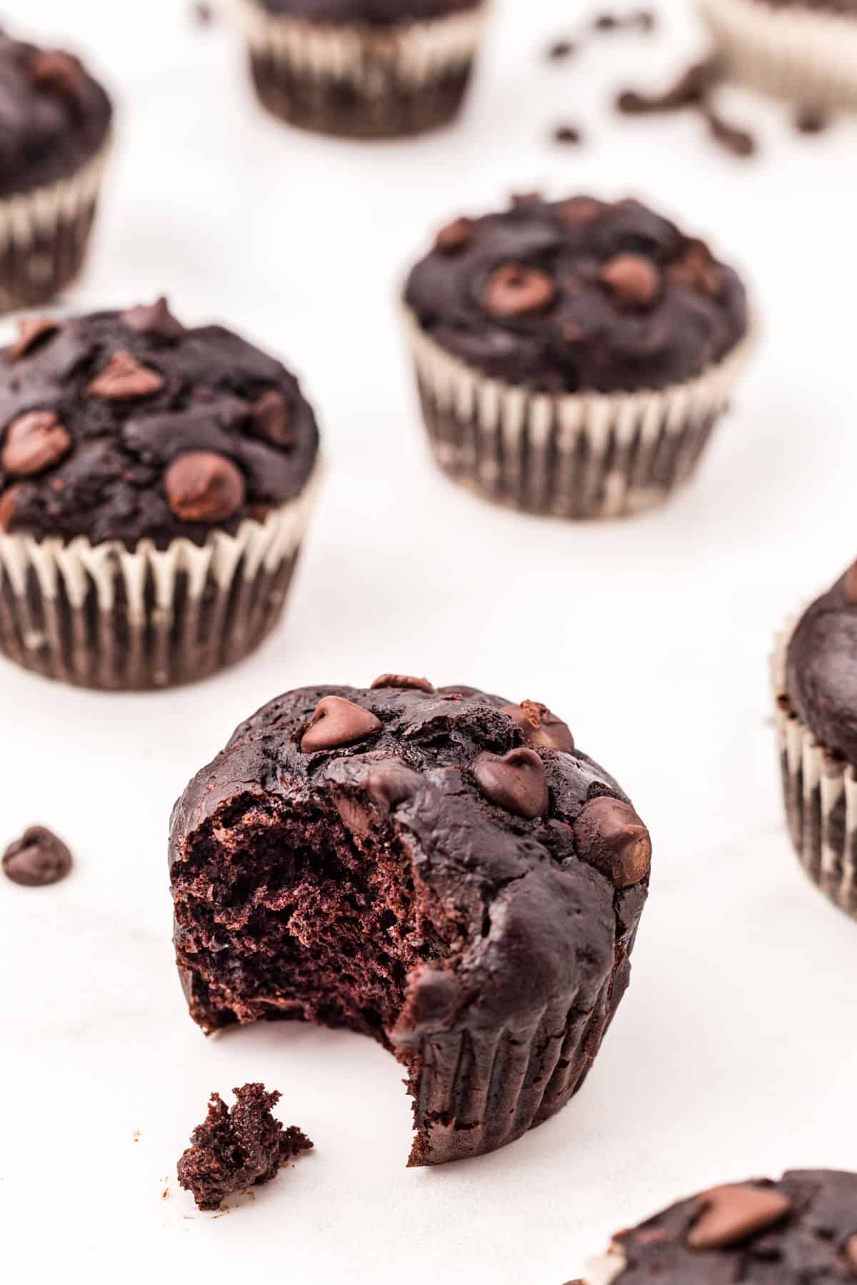 Chocolate zucchini muffins with one bite removed.