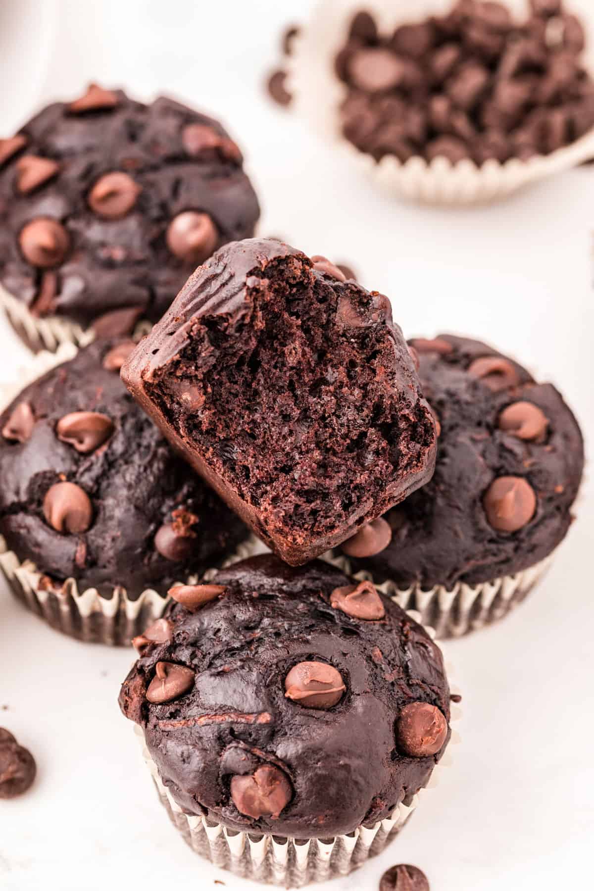 Chocolate zucchini muffins stacked on a counter.
