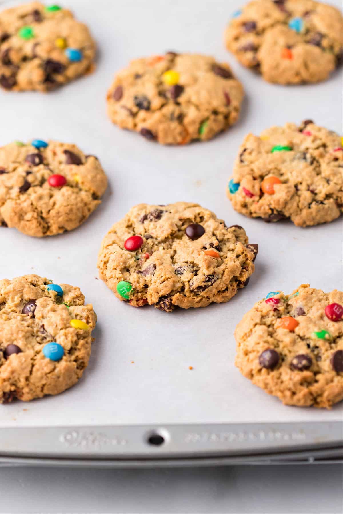 Monster cookies baked on a parchment paper lined cookie sheet.