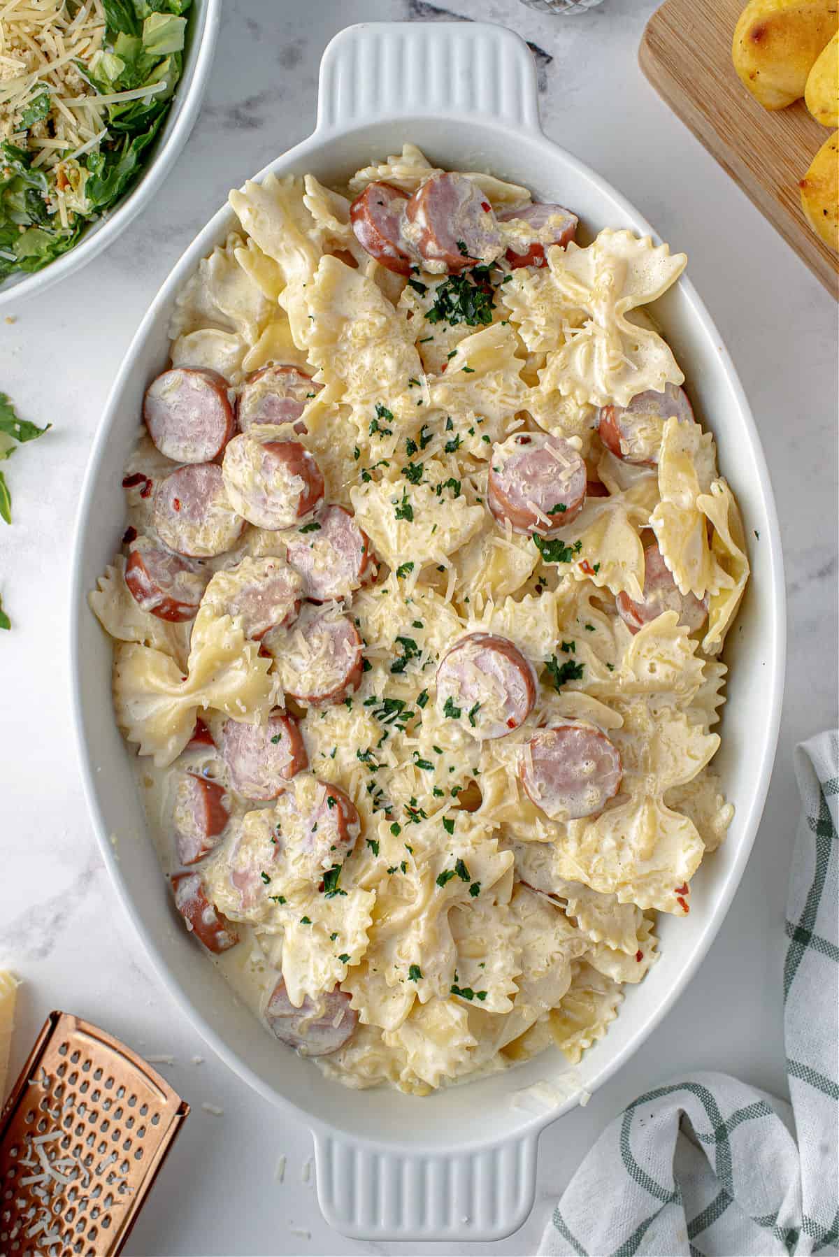 Sausage alfredo pasta served in a large oval baking dish.