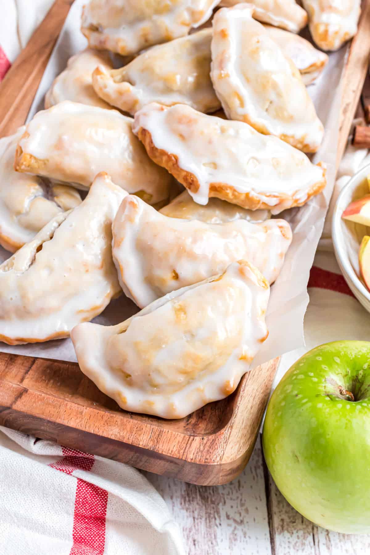 Apple hand pies stacked on a wooden board.