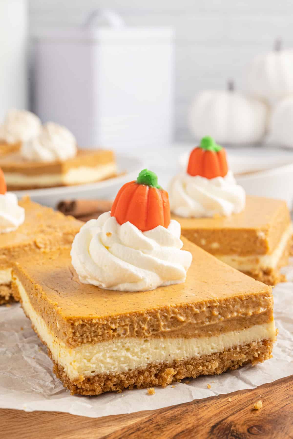 Pumpkin cheesecake bar garnished with whipped cream and candy corn pumpkins.