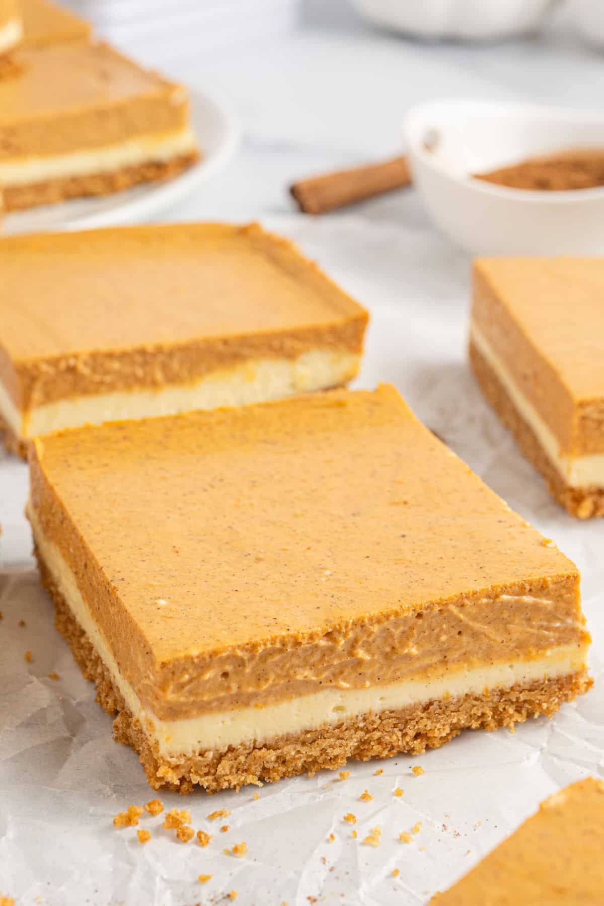 Slice of pumpkin cheesecake bar on parchment paper.