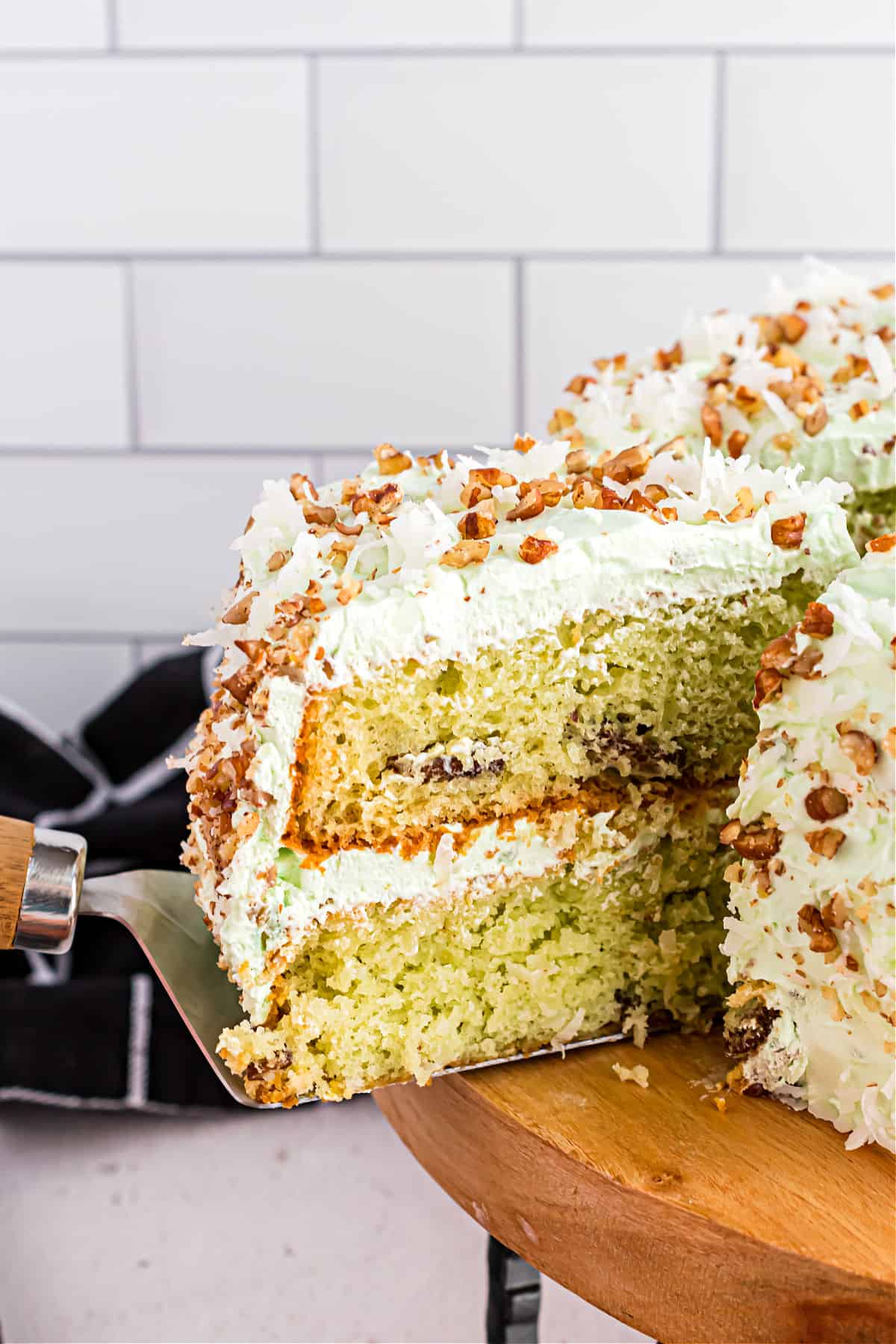 Watergate cake with pistachio pudding, coconut, and pecans on cake platter.