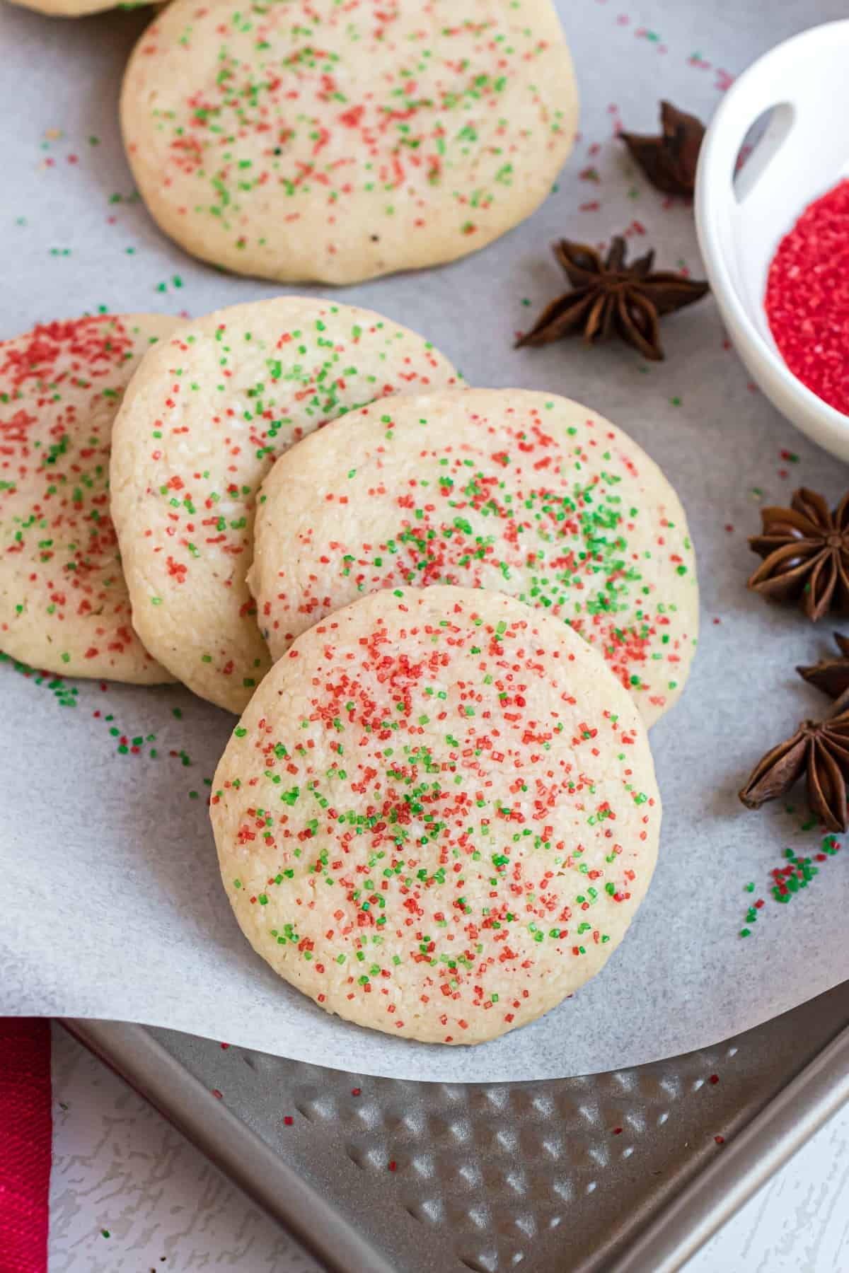 Anise cookies with red and green sprinkles on parchment paper baking sheet.