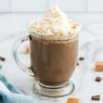 Caramel mocha with whipped cream in a clear glass mug.