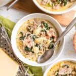A bowl of creamy low carb keto zuppa toscana with sausage, spinach, cauliflower, and shredded cheese, served with a spoon in the bowl.