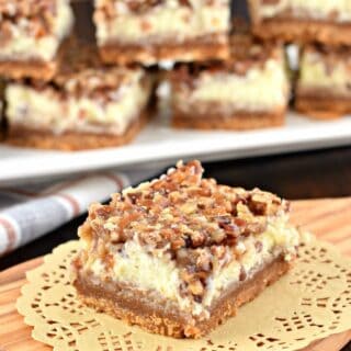 The layers on these Pecan Pie Cheesecake Bars are incredible! One tasty bite and you'll fall in love! From the graham cracker crust, to the sweet cheesecake filling and the pecan pie topping, this holiday dessert receives rave reviews from everyone!