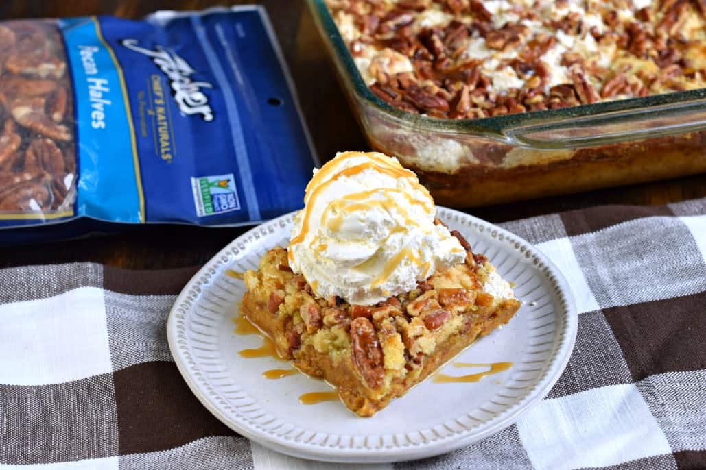 Pumpkin dump cake on a plate with vanilla ice cream and caramel sauce.